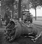 Canadians in Holland. Pte. J.E. Kirby of Queen's Own Camerons of Canada stands guard over a V-bomb motor near the Antwerp Docks. Apparently a new type of stratosphere bomb, jet propelled 15 October 1944.