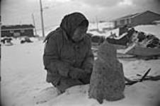 [Kenojuak Ashevak sculpting outside] December 1980