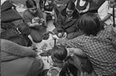 [Kenojuak Ashevak and family eating seal at home] November 1980