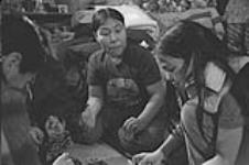 [Kenojuak Ashevak and family eating seal at home] December 1980