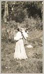 [Anishinaabe woman with baby in a tartan cloth tikinagan on her back] 1919