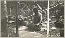 [Anishinaabe man winnowing the hulls from manoomin (wild rice)] 1919