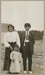 [Anishinaabe woman, child, and man standing outside] 1920
