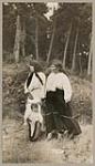 [Two Anishinaabe women and baby in a tartan cloth tikinagan] 1920