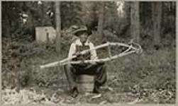 [Seated Anishinaabe man displaying snowshoe frames ready for drying] 1920