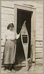 [Anishinaabe woman at Lac Seul displaying a snowshoe with partially completed netting] 1920