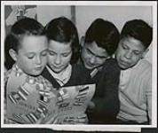 [Group of unidentified children looking at a Junior Red Cross book] [ca. 1950-1960]