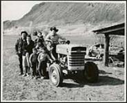 [Group photo of people on a farm, posing with a tractor] [ca. 1950-1960]