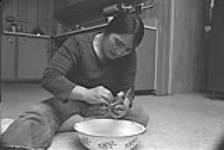 [Ovilu Tunnillie polishing a sculpture at home] December 1980