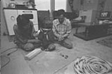 [Abraham Etungat and Itigayaqyuaq Etungat working on a sculpture at home] December 1980