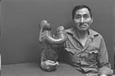 [Studio portrait of Abraham Etungat with one of his sculptures] December 1980