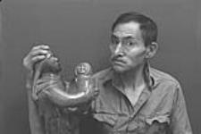 [Studio portrait of Abraham Etungat with one of his sculptures] December 1980
