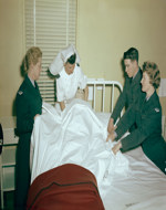 Students under supervision move patient from stretcher to bed following operation 12 March 1957.