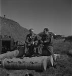Lieut. N.E. Bush, Southsea, Eng. section commander and B.S.M. James Hore, Sheerness, England sitting on empty cordite cases - both on No. 1 gun, Wanstone Bty 17 September 1944.