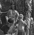 [Miss Dianne Smith in the background, a young Haudenosaunee girl who played the part of Pauline Johnson during the Six Nations Pageant, and in the foreground can be seen two young Haudenosaunee girls making up some props for the presentation in the Forest Theatre]. Original title: Photograph shows Miss D. Smith in the background, a young Indian girl who played the part of Pauline Johnson during the Indian Pageant, and in the foreground can be seen two young Indian girls making up some props for the presentation in the Forest Theatre August 1961
