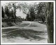 [Stretch of paved and painted road in Rockcliffe with rock wall on the left side] [1927-1932].