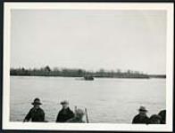 [Floating barge on river with workers in foreground] cira 1924-1928.