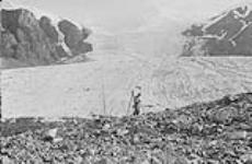 Surveyor looking up a small tributary glacier, 141st Meridian, Kluane Glacier, Y.T