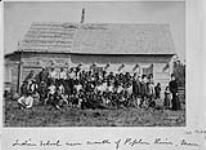 Élèves et parents autochtones avec leurs enseignants à l'extérieur d'une école indienne, près de la rivière Poplar (Manitoba), 1890 1890.