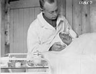 [Médecin effectuant une opération sur un enfant inuk non identifié, Kangiqsujuaq, Nunavik] Titre original: Dr W.J.K. Clothier opérant sur un enfant esquimau, Wakeham Bay (Québec) 1928.