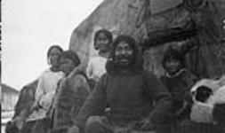 Arnaujaq (extreme left), Akumalik (foreground), Idlout (right), N.E. coast of Baffin Island. [Left to right): Arnaujaq, Illauq, Niigug Inuujaq, Akumalik and Moses Ittukusuk. This photograph was taken outside of Akumalik's home.] 17 Sept. 1924