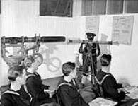 An instructor demonstrating the operation of a rangefinder at the Royal Canadian Navy Gunnery School, H.M.C.S. CORNWALLIS, Halifax, Nova Scotia, Canada, February 1941 February, 1941.