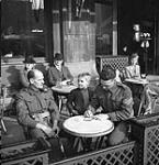 Sergeant G.S. Coen (right), Royal Canadian Army Service Corps (R.C.A.S.C.), signing autograph book for boy at café. Sergeant C.C.W. Campbell, Canadian Dental Corps (C.D.C.), is at left, Antwerp, Belgium, 17 September 1944 September 17, 1944.