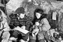 Inuit man and woman with child, examining a document 1949