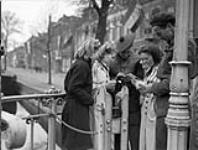 Private J.L. Davies of The Lorne Scots (Peel, Dufferin and Halton Regiment) (centre) and Private W. Mahar of 9th Canadian Infantry Brigade Headquarters signing autographs, Leeuwarden, Netherlands, 16 April 1945 April 16, 1945.