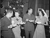 Lieut. H.N. Young, R.C.A., Faith Watson, Canadian Red Cross Society, Lieut. L.L. Langsner, R.C.A., and Margaret Gilbert, Canadian Red Cross Corps at Maple Leaf 2 Club 25 Dec. 1943