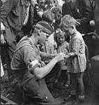 Private G.R. MacDonald of The Toronto Scottish Regiment (M.G.) giving first aid to an injured French boy, Brionne, France, 25 August 1944 August 25, 1944.