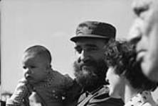 Cuban Prime Minister Fidel Castro holding an infant while Mrs. Trudeau and Prime Minister Pierre Elliott Trudeau look on during their Latin American Tour Jan. 1976
