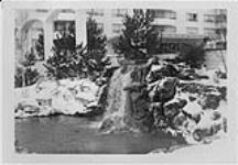 Winter view of garden with waterfall, designed by J. Austin Floyd, Delzotto apartment building, Lawrence Avenue and Keele Street 1963