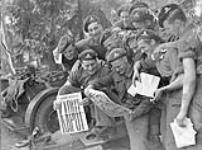 Gunners of the 12th Field Regiment, Royal Canadian Artillery (R.C.A.), with the Victory issue of the Maple Leaf newspaper, Aurich, Germany, 20 May 1945 May 20, 1945