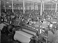 Des ouvrières travaillent sur des métiers à tisser à la manufacture de textiles de la Montreal Cottons ca. Mar. 1942