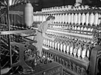 À la manufacture de textiles de la Montreal Cottons, une ouvrière surveille le fonctionnement du banc à broches vers 1945