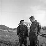 James Houston, area administrator chatting with his Inuit interpretor Jonahssie, Cape Dorset, N.W.T., [(Kinngait), Nunavut], August 1961 August 1961.