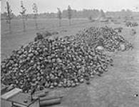 German prisoners of war, under guard, sort through hugh piles of helmets and respirators 17 May 1945
