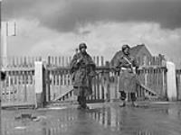 Captain M.D. Matterson guarding the barracks entrance with his armed enemy companion 2-5 May 1945