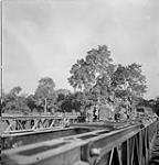 Infantrymen of the Stormont, Dundas and Glengarry Highlanders crossing the Orne River on a Bailey bridge built by the Royal Canadian Engineers (R.C.E.) en route to Caen, France, 18 July 1944 July 18, 1944.