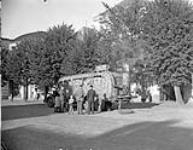 "German civilian transport is very weak. With full steam up on his wood burnign bus, this driver has stopped in the town square to change a tyre while passengers pile out to watch" 26-27 Aug. 1945