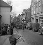 Germany prisoners marching through town while Canadian Army vehicles move forward to the front 5 Apr. 1945