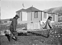 Logement au poste de la Hbc. (Compagnie de la Baie d'Hudson). [Akumalik (à gauche) et Maki Angutirjuaq (à droite) en train de décharger un pont maritime.] 1 Septembre 1922