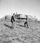 Captain Kingston and Lance-Corporal E.R. Volpe of the 4th Canadian Infantry Brigade examining a camouflaged German command post north of Nieuport, Belgium, 13 September 1944 September 13, 1944.