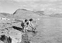 [Moses Idlout (left) and Rebecca Qillaq Idlout (right) soaking "kamiks".] 1951