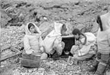 [Left to right: Jimaima Angiliq, Gamailie Kilukuishak, Mary Aaluluuq Kilukuishak and Angutirjuaq. Jimaima Angiliq was pregnant and Mary Kilukuishak was carrying a little boy named Miskaki. Kilukuishak was trying to start a small stove for hot water.] 1951
