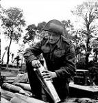 Bombardier L.A. Boyle, 34 Battery, 14th Field Regiment, Royal Canadian Artillery (R.C.A.), inserting a cartridge in a 105mm. shell, France, 20 June 1944 June 20, 1944.