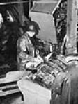 Unidentified worker using the Smith Butchering Machine at the salmon cannery / Travailleur utilisant une machine à dépecer Smith dans une saumonerie de Namu Aug. 1945