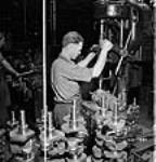 Workman drills metal from counterweights of crankshafts in the machine shop at the Ford Company of Canada plant 2 July 1942