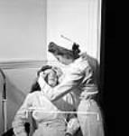 L'infirmière Françoise Trudel, à la fabrique Dominion Arsenals Ltd., enlève de la cendre de l'oeil de l'employée Hélène Perry 24 Aug. 1942